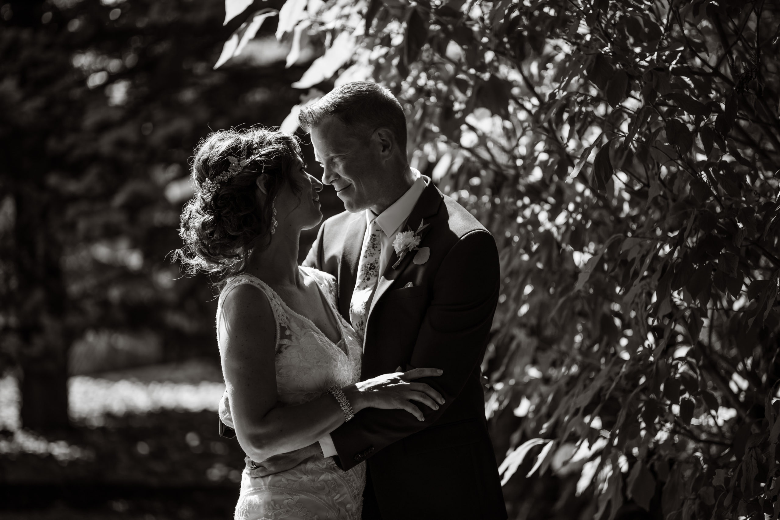 A bride and groom smile at each other during their backyard wedding