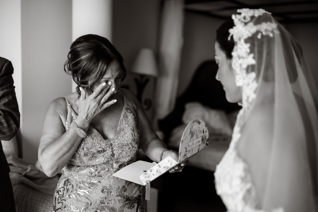 The mother of the bride wipes away a tear from her eye while reading a card from her daughter before a Caribbean Destination Wedding photographed by TKM Photography located in Roatan, Honduras and Durham Region, Ontario