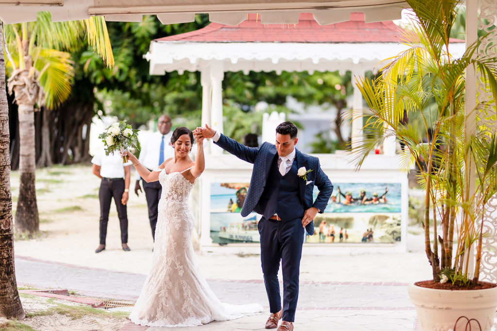 A bride and groom dance into their reception at their Caribbean Destination Wedding photographed by TKM Photography located in Roatan, Honduras and Durham Region, Ontario, while her sister plays traditional wedding songs behind them. 