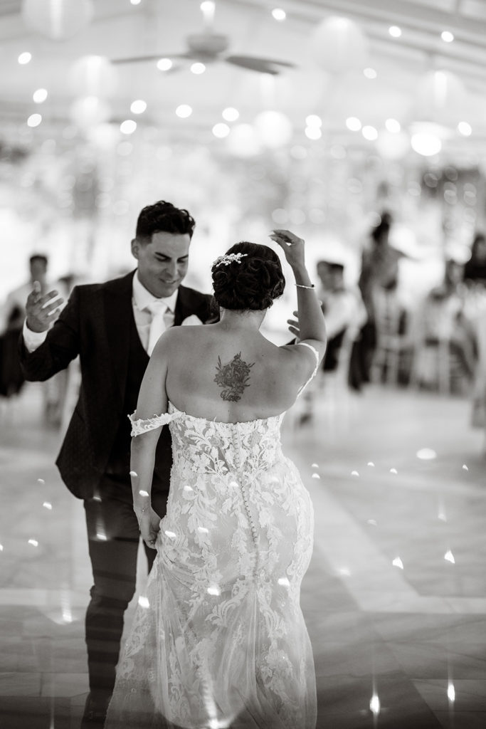 A bride and groom dance salsa at the reception of their Caribbean Destination Wedding photographed by TKM Photography located in Roatan, Honduras and Durham Region, Ontario, while her sister plays traditional wedding songs behind them. 